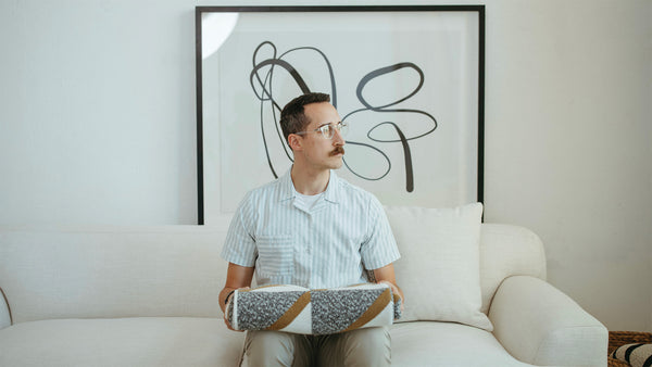 Cool Art and Guy Sitting on White Sofa with a Neutral Cotton Throw Blanket