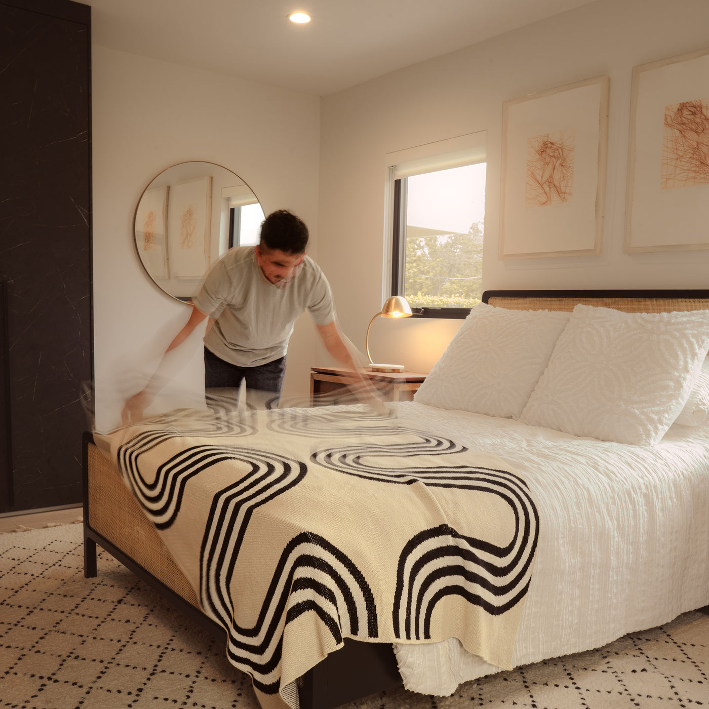 Guy making the bed with a throw bold throw blanket