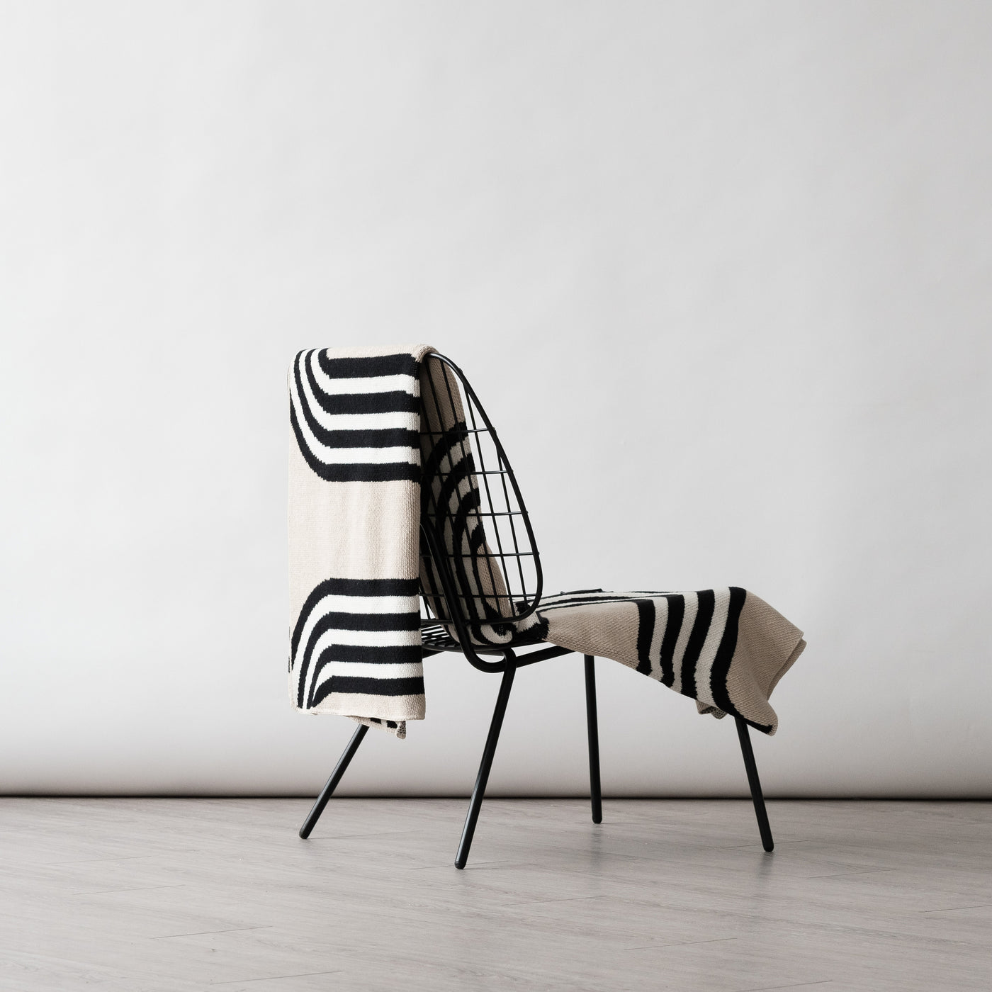 Low wire black chair with a modern beige throw