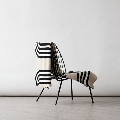 Low wire black chair with a modern beige throw