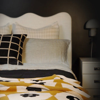 Black Bedroom with Gold Flower Throw and White Wavy Headboard