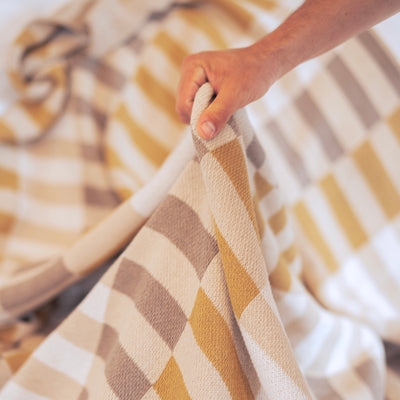 Man Holding a Gold and Taupe Throw