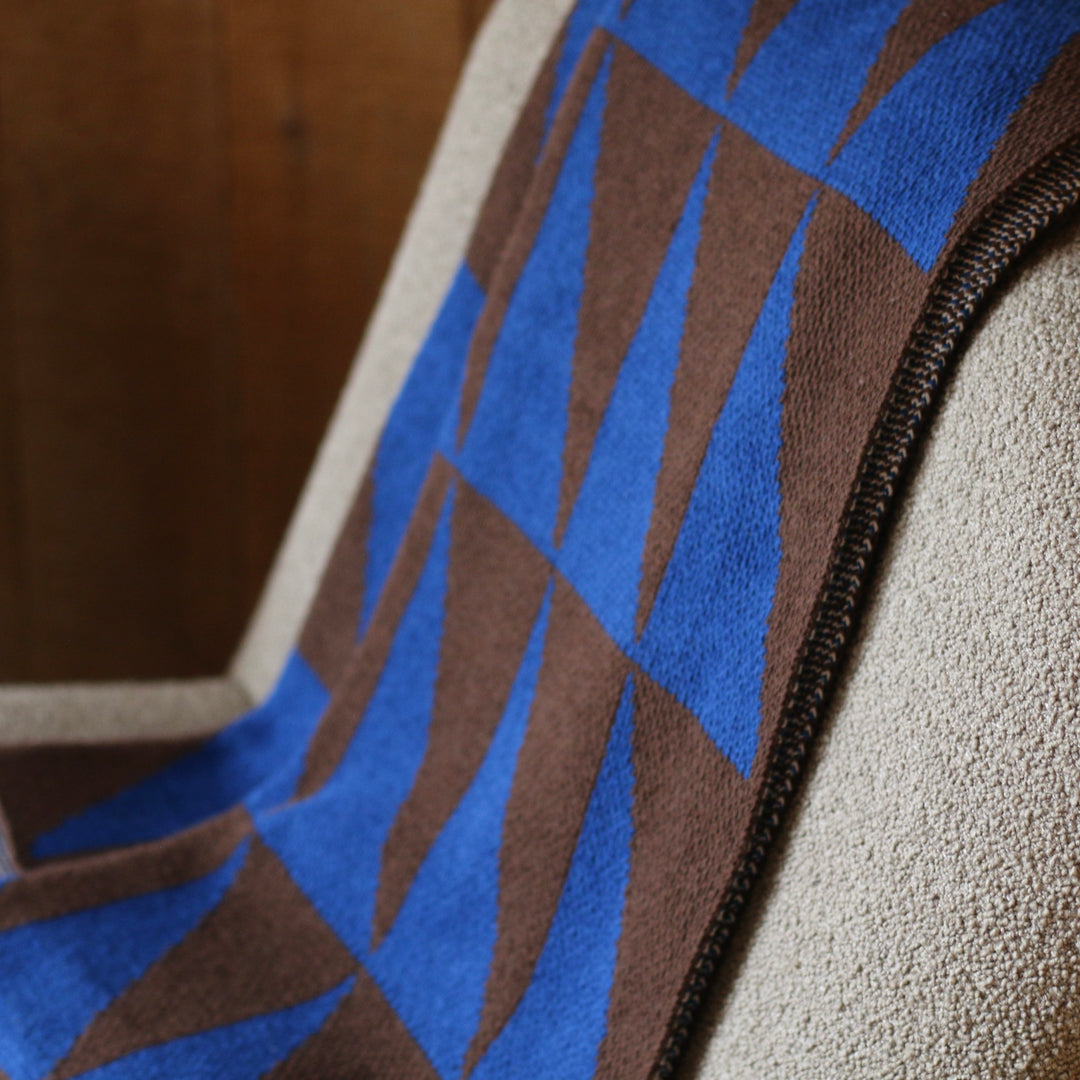 Close-up of a fabric with blue and brown pattern throw blanket on a textured surface