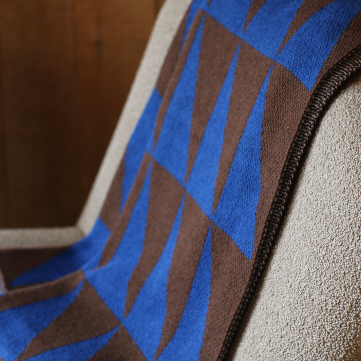 Close-up of a fabric with blue and brown pattern throw blanket on a textured surface
