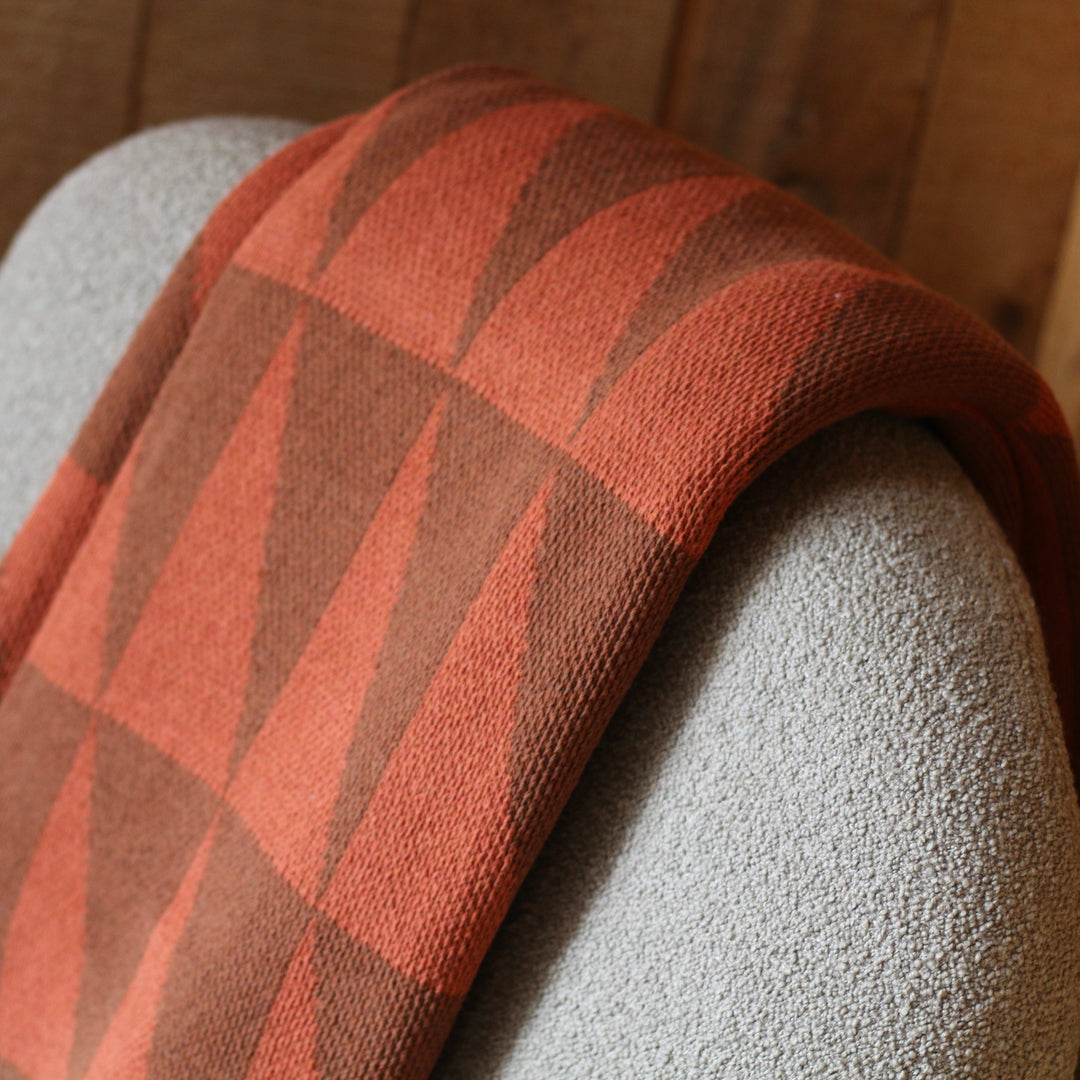 Throw blanket with geometric pattern draped over a textured surface