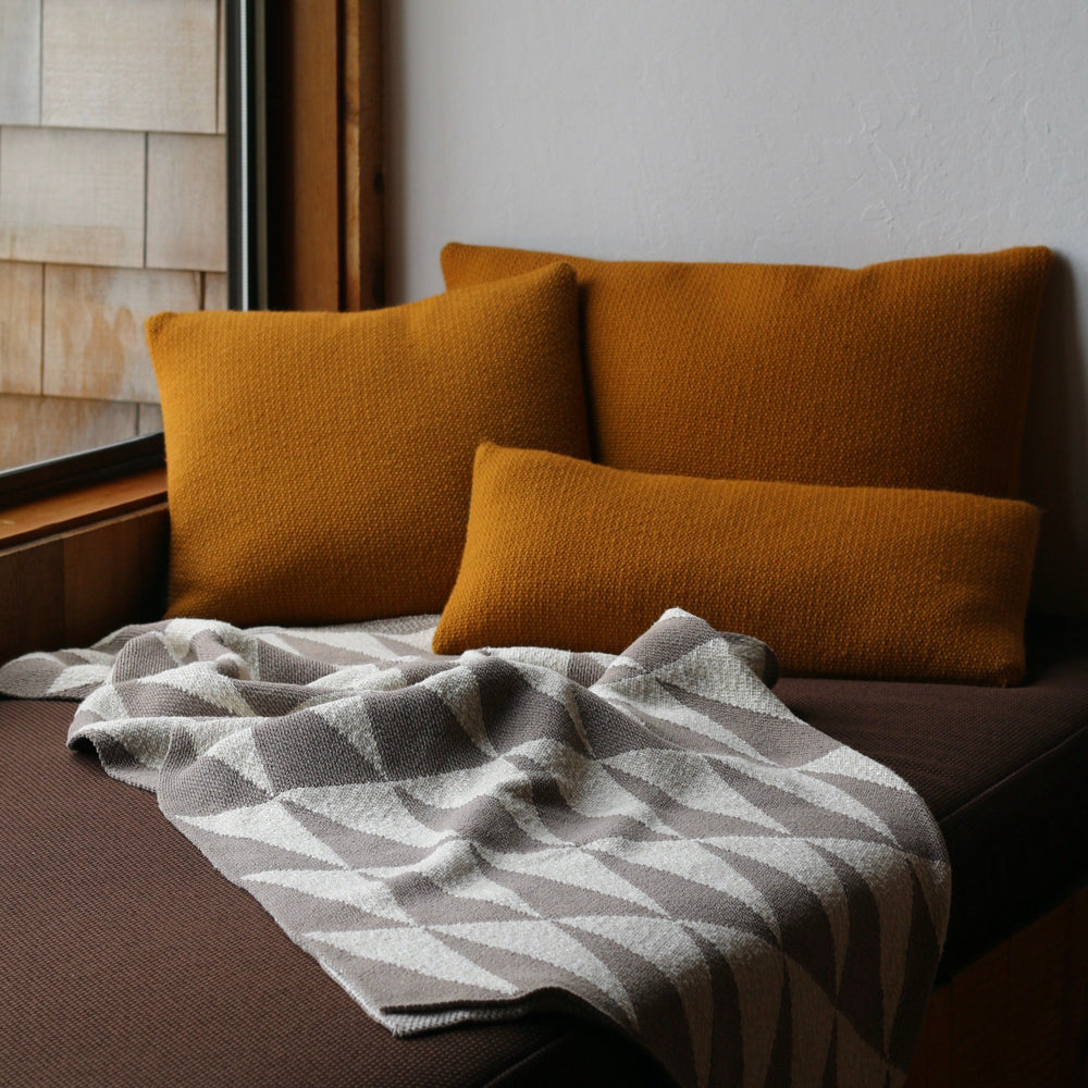 Gold cushions on a sofa with a taupe and white patterned blanket