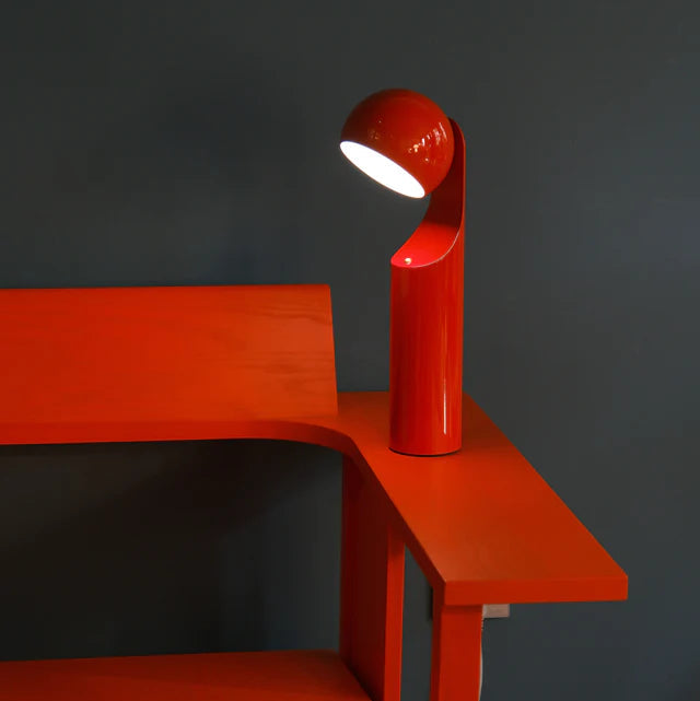 Red lamp on a red shelf against a dark background