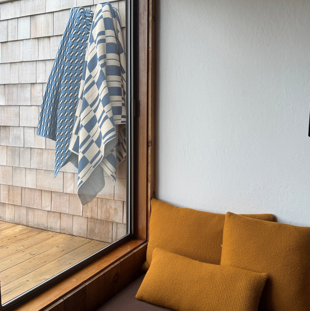 Window seat with cushions and patterned modern throw blankets on a wooden deck