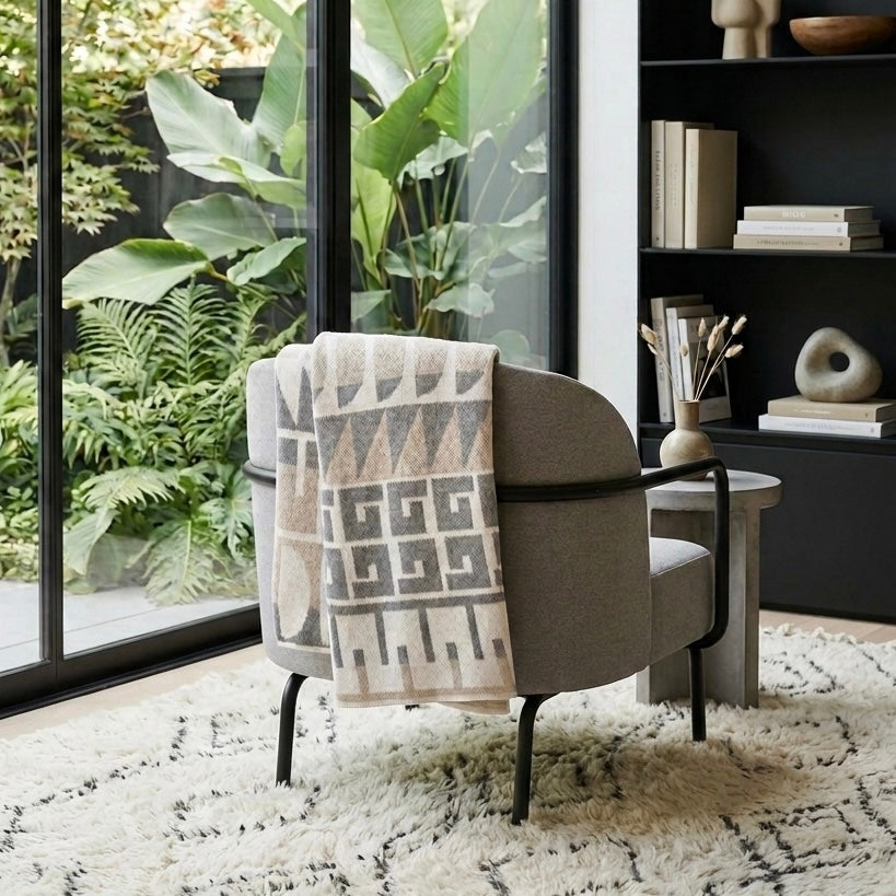 Chair with a patterned blanket in a room with plants and shelves