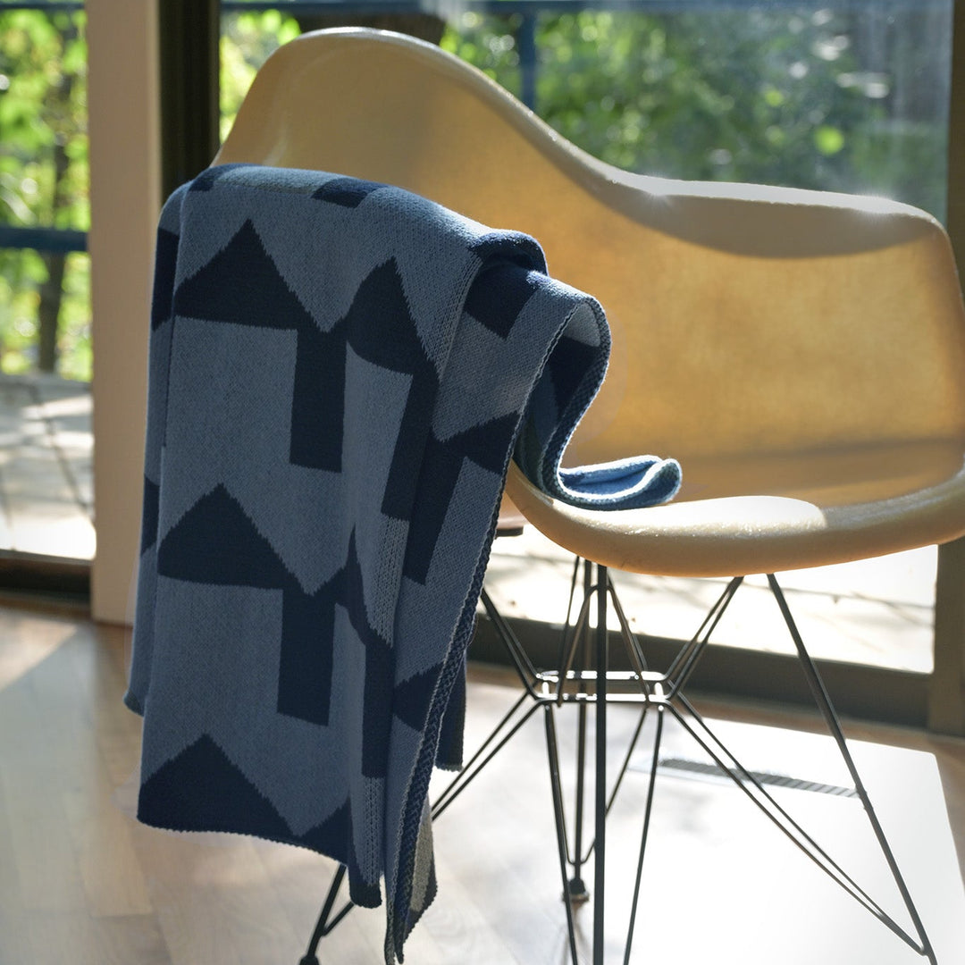 BLUE HOUSES PATTERN THROW ON A CREAM EAMES FIBERGLASS CHAIR