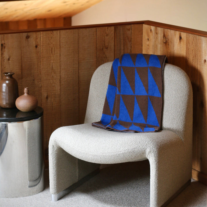 Chair with a blue and brown patterned blanket in a room with wooden walls and ceiling.