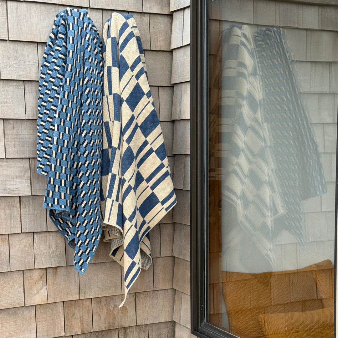 Two blue and white patterned throws hanging on a wooden wall.
