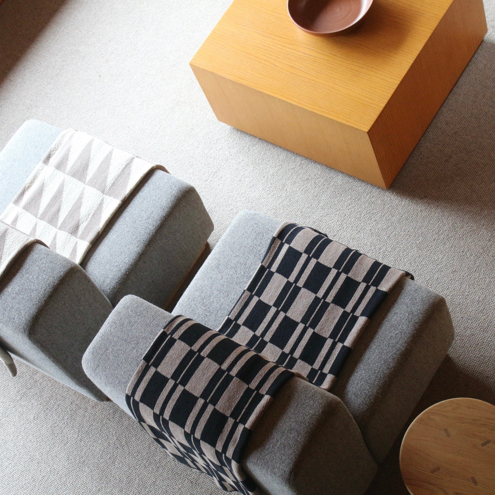 Gray chair with patterned throw blanket on a light gray floor.