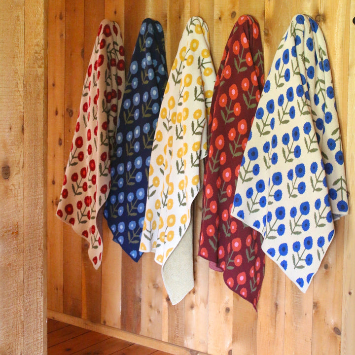 Set of colorful patterned throw blankets hanging on a wooden wall.