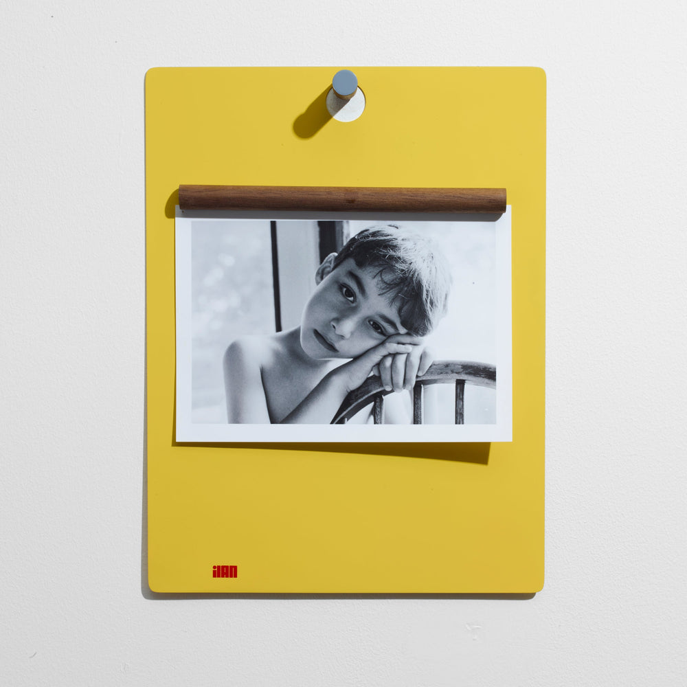 Yellow hanging clipboard with a black and white photo of a person on a light gray background