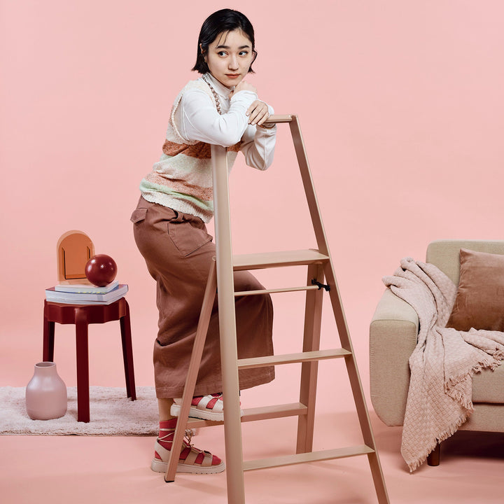 Woman standing on a mauve ladder against a pink background