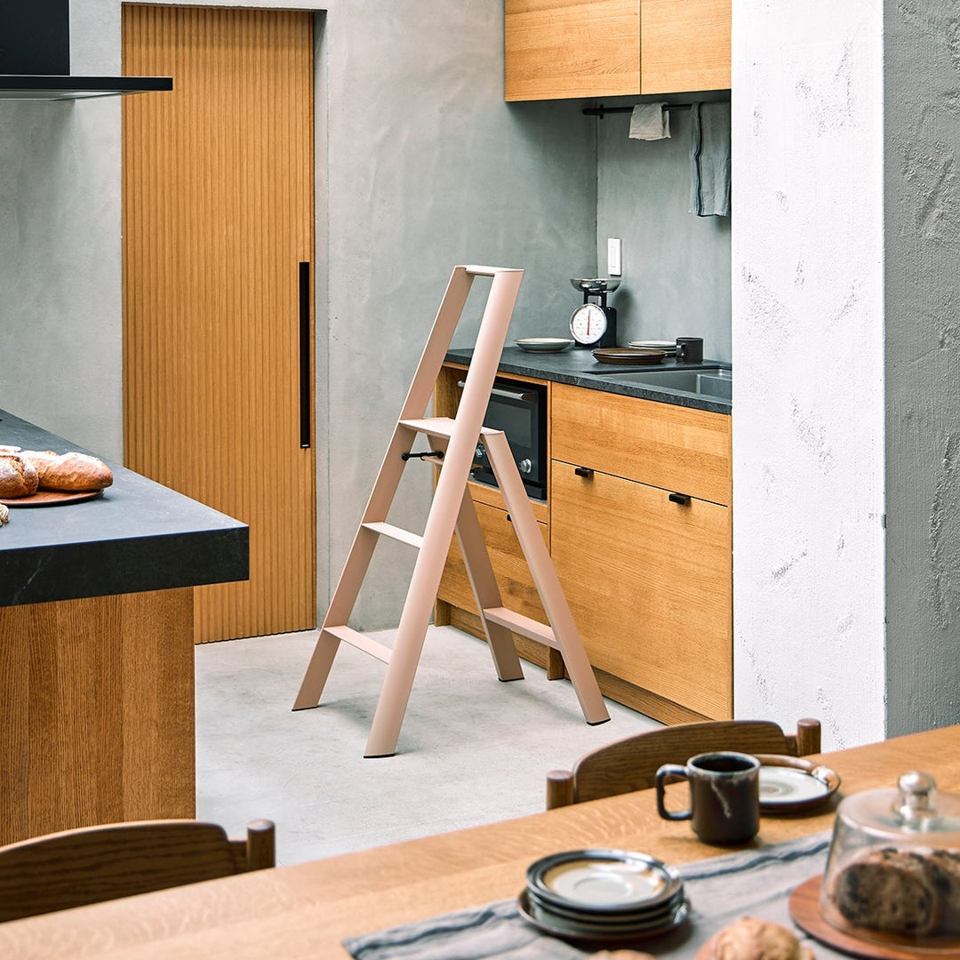 Modern kitchen with wooden cabinets, a dining table, and a ladder.