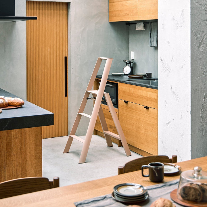 Modern kitchen with wooden cabinets, a dining table, and a ladder.
