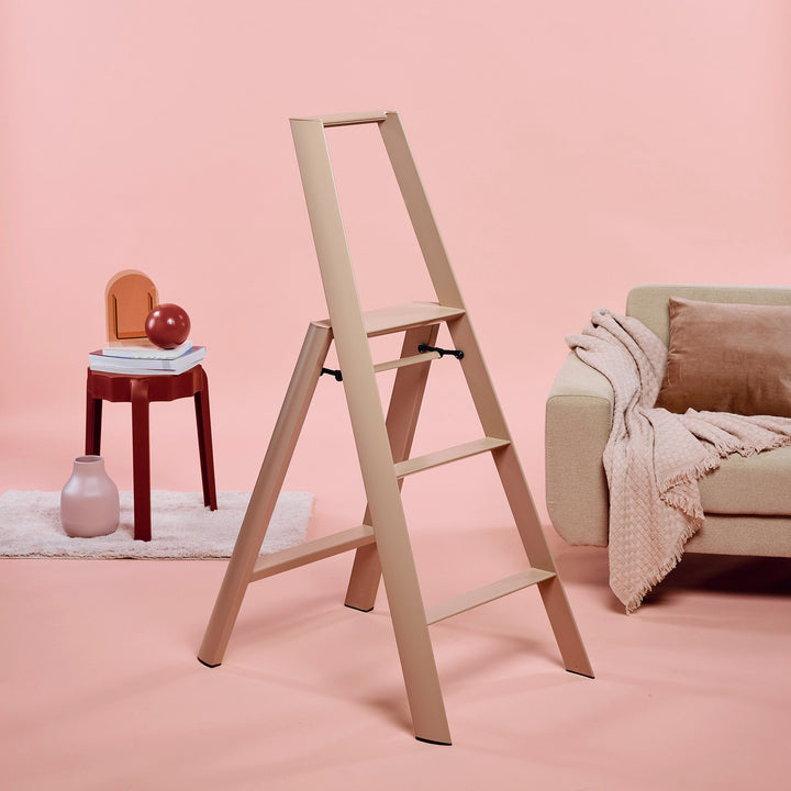 mauve step ladder in a room with pink walls, a chair, and a sofa.