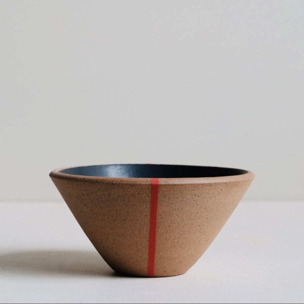 Ceramic bowl with a red stripe on a light surface