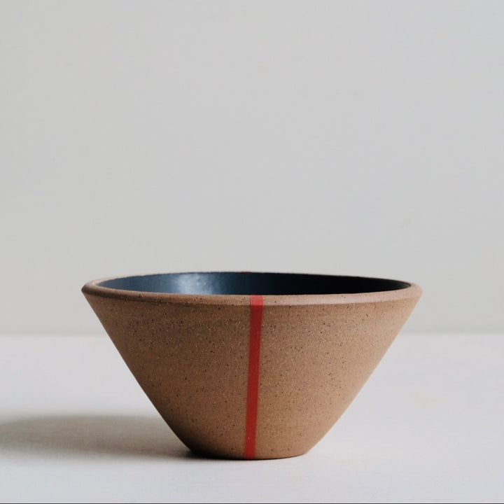 Ceramic bowl with a red stripe on a light surface