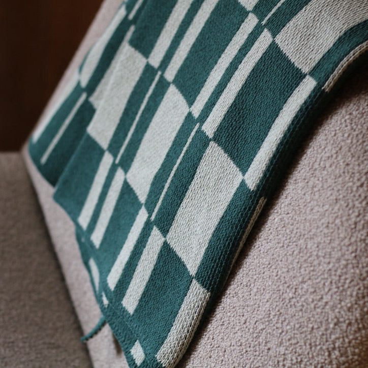 Green checkered blanket draped over a textured surface