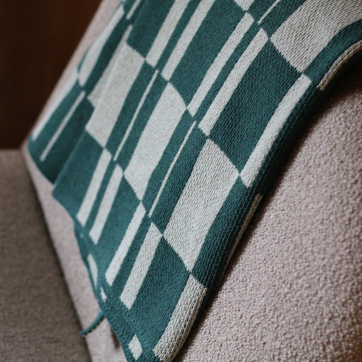 Green checkered blanket draped over a textured surface