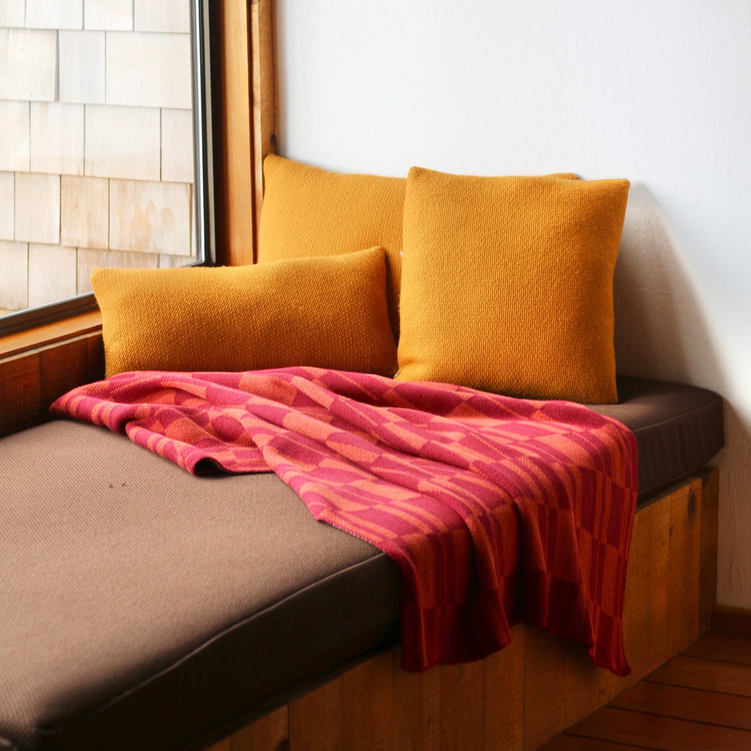 Nook with cushions and a blanket by a window