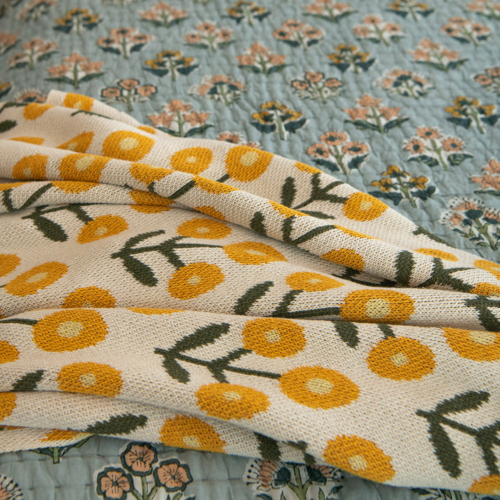 Tossed throw blanket with yellow floral pattern on a floral background