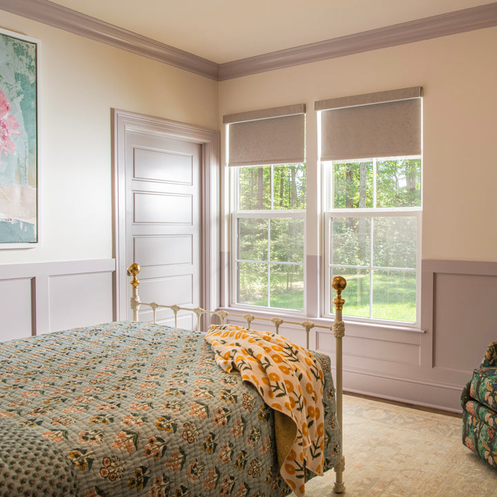 Bedroom with floral bedspread, yellow floral throw and window view