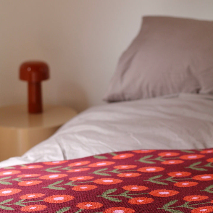 FLORAL THROW BLANKET IN BURGUNDY AND RED AND PINK ON A BED