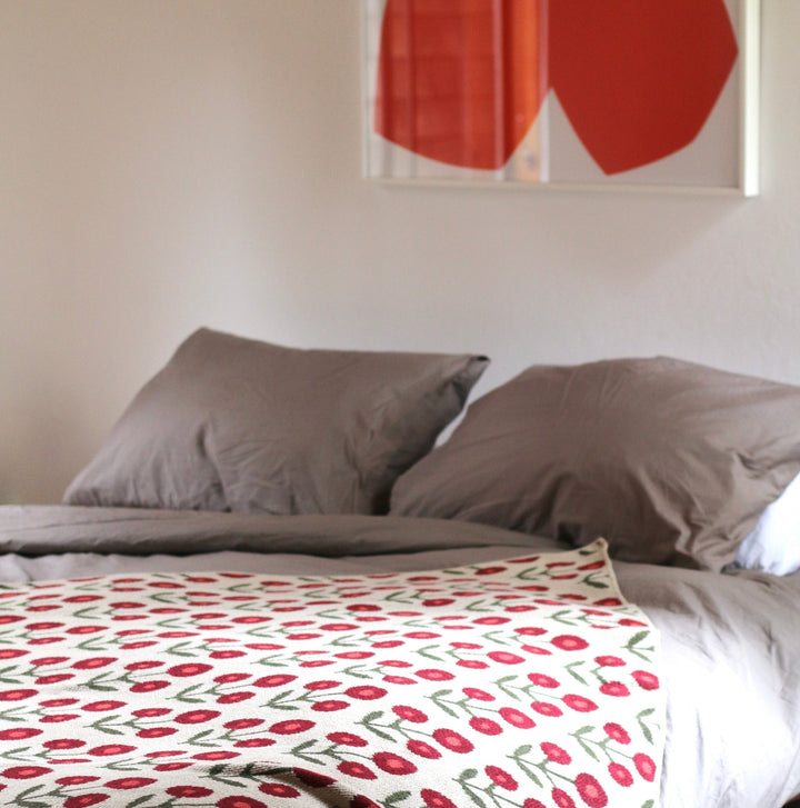 Bed with patterned blanket and gray pillows, red abstract art on wall