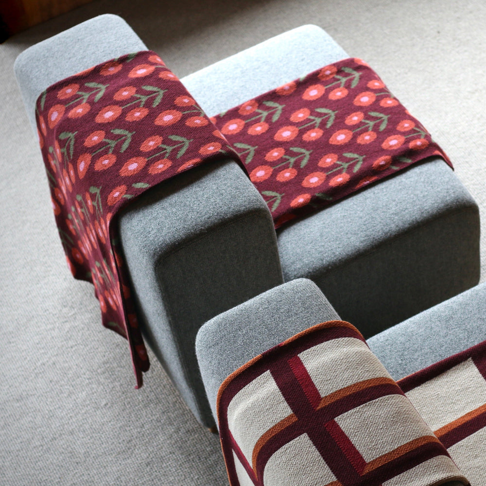 Patterned blankets draped over a gray sofa on a light-colored floor.