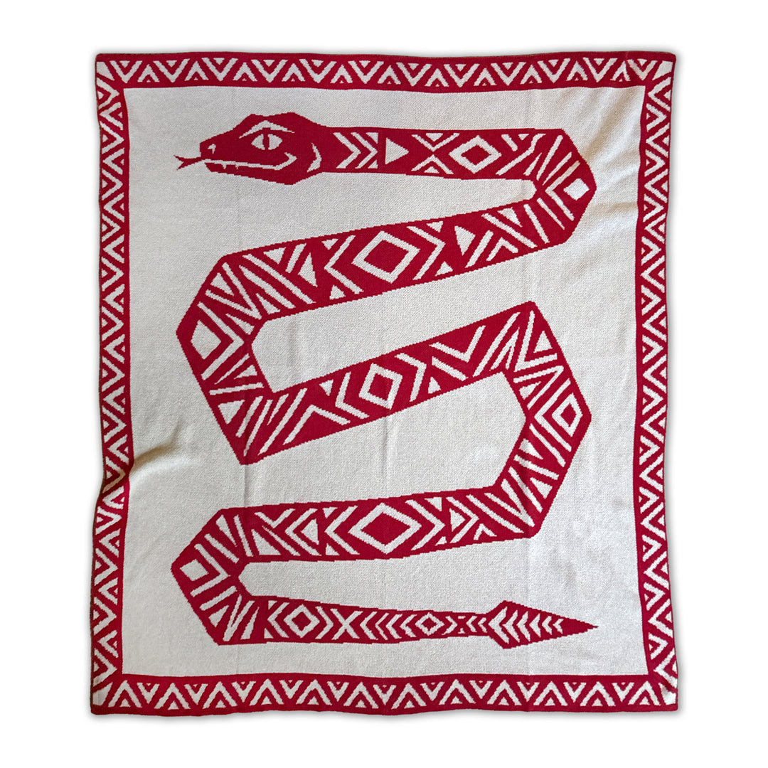 A knitted throw blanket featuring a large red snake with geometric patterns on a beige background, bordered by a red and beige patterned edge.