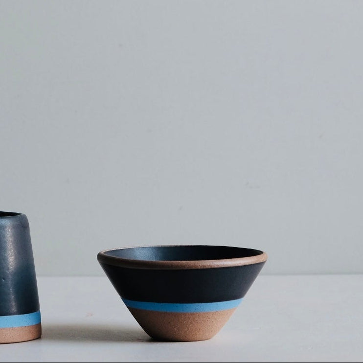 Two ceramic mugs with blue and brown accents on a light gray background