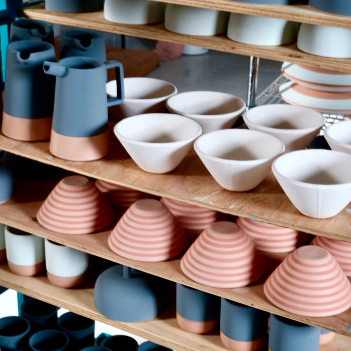 Shelves displaying a variety of ceramic bowls and vases in different colors.