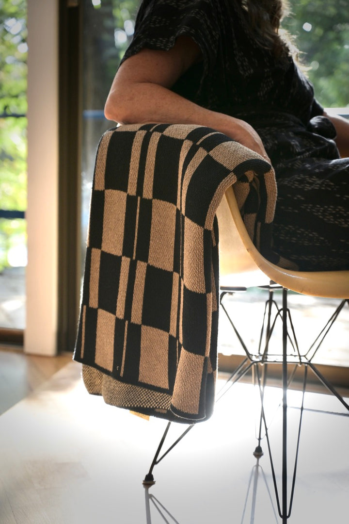 modern checked throw blanket on an eames fiberglass chair with person