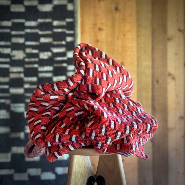 Red and white checkered fabric on a wooden stool against a textured wall.