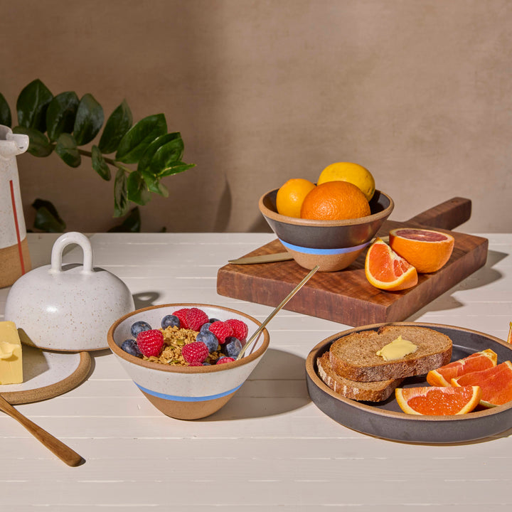Breakfast setup with a bowl of fruit, bread, and orange slices on a table.